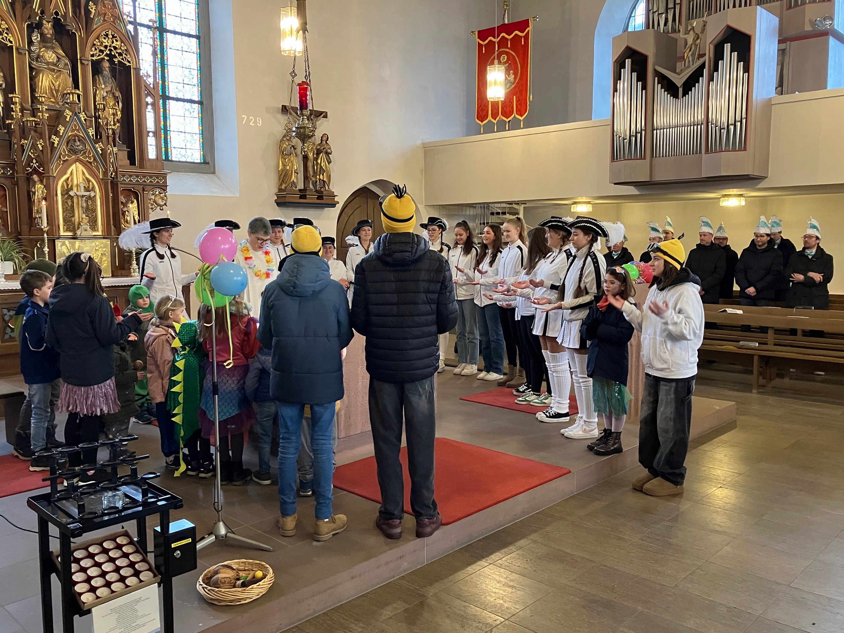 In der Kirche St. Martin in Burggrumbach stehen Kinder und Jugendliche in Faschingskostümen um den Altar.