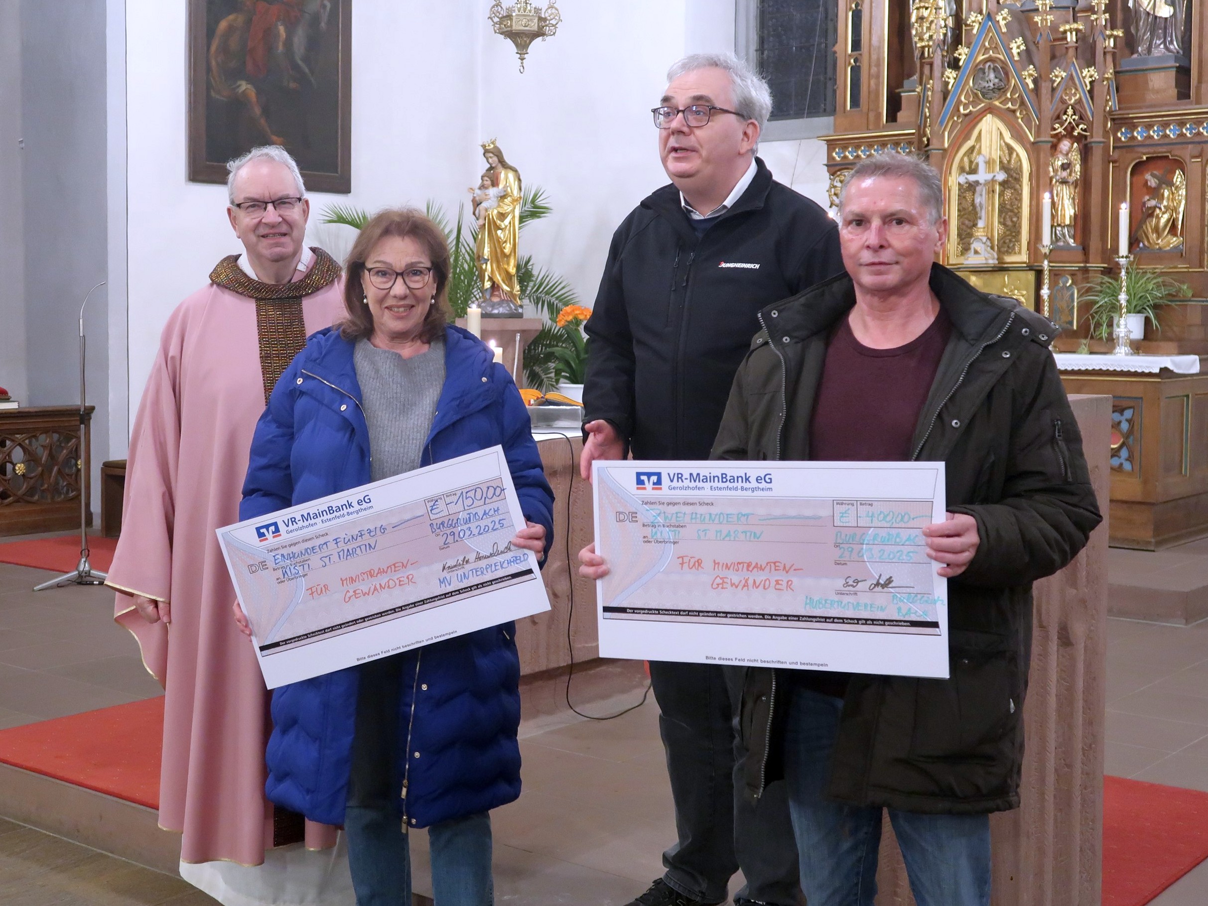 In der Burggrumbacher Kirche werden zwei große symbolische Schecks übergeben. 