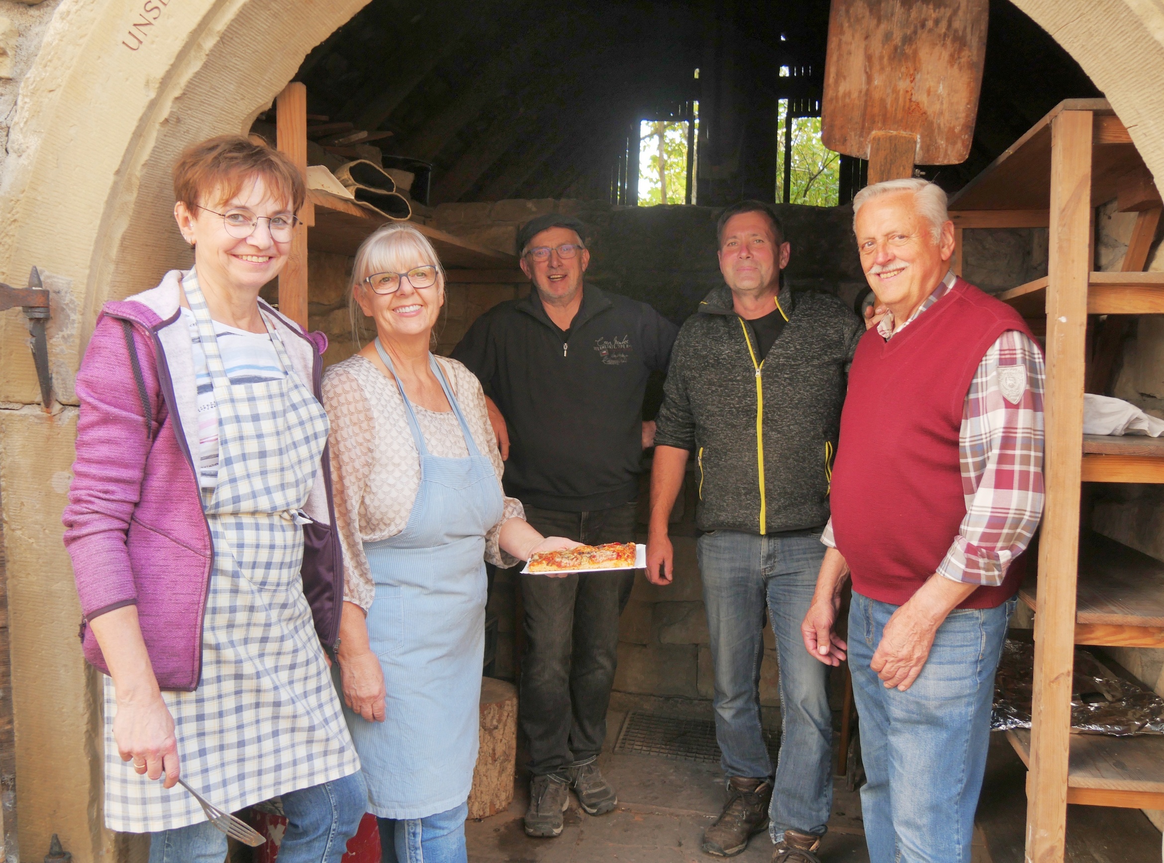 Das Bild zeigt fünf Personen, die in die Kamera schauen. Im Hintergrund ist der Backofen zu sehen.