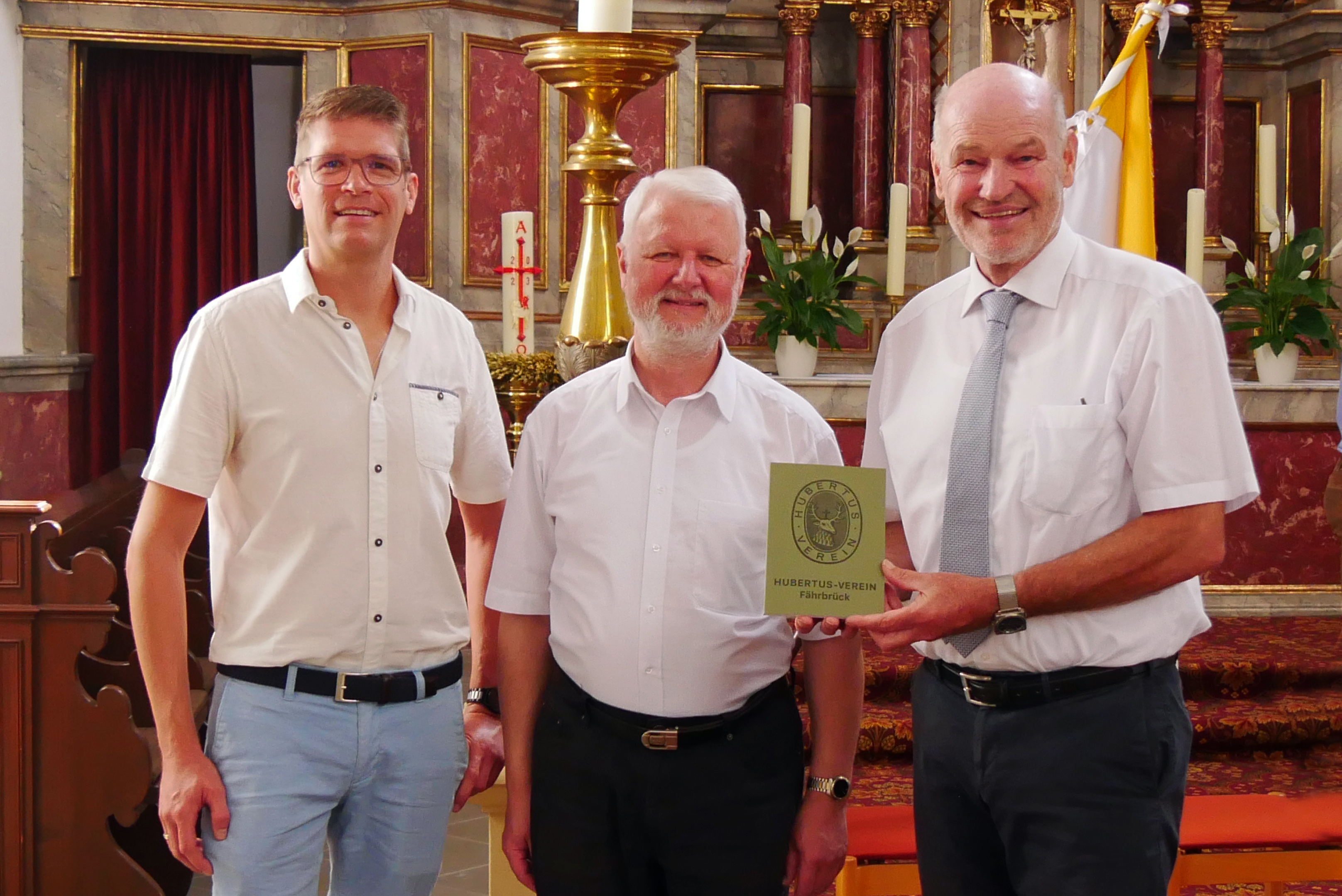 Drei Männer bei der Übergabe eines Geschenkes.