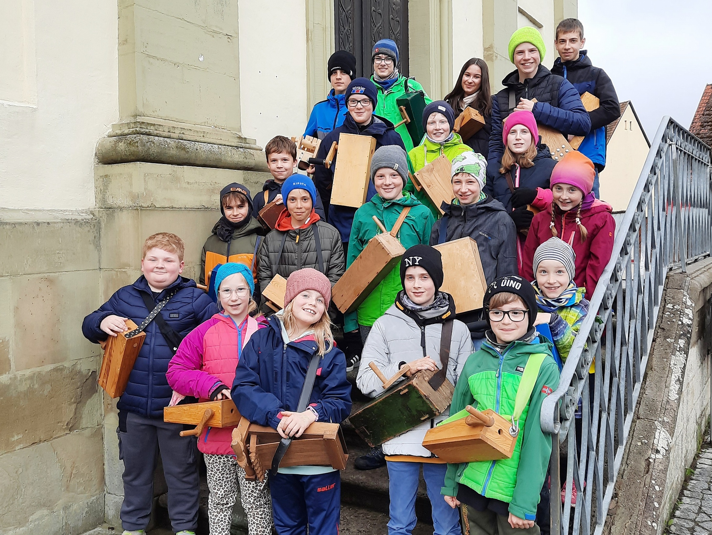 Auf der Kirchentreppe stehen viele Kinder mit ihren Rappelkästen.