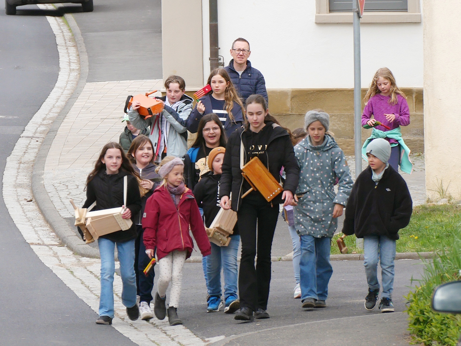 Eine Gruppe Rappelkindern kommt auf einer Dorfstraße entgegen.