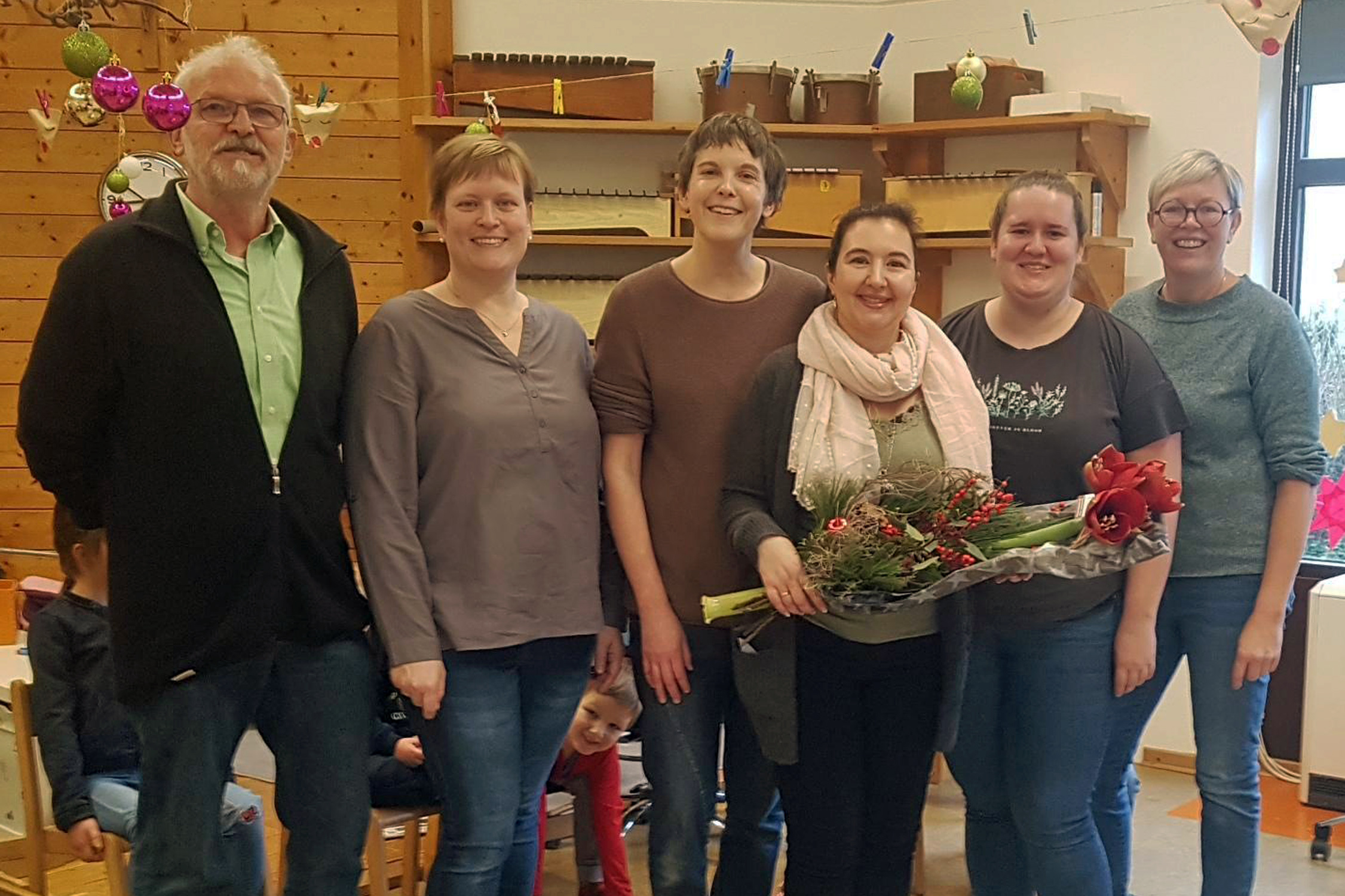 Auf einem Gruppenbild mit sechs Personen hält die Jubilarin einen Blumenstrauß in der Hand.