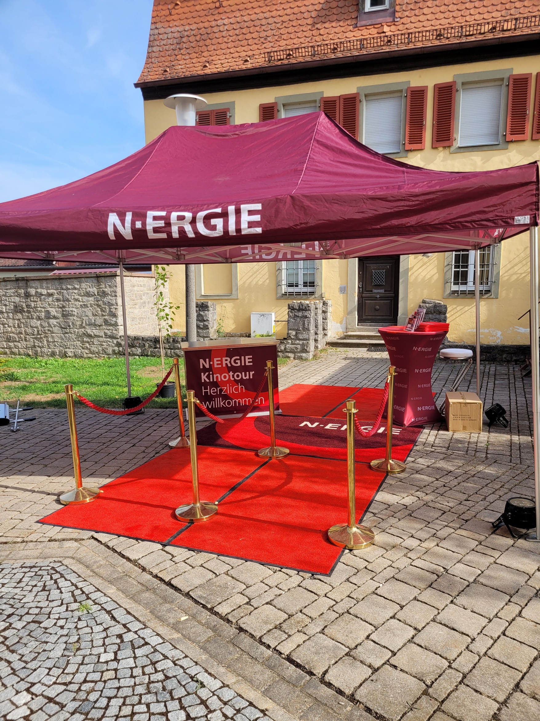 Ein Pavillon der N-Ergie und ein roter Teppich zur Begrüßung sind vor dem Pfarrhaus und dem Eingang zum Pfarrgarten in Prosselsheim aufgebaut