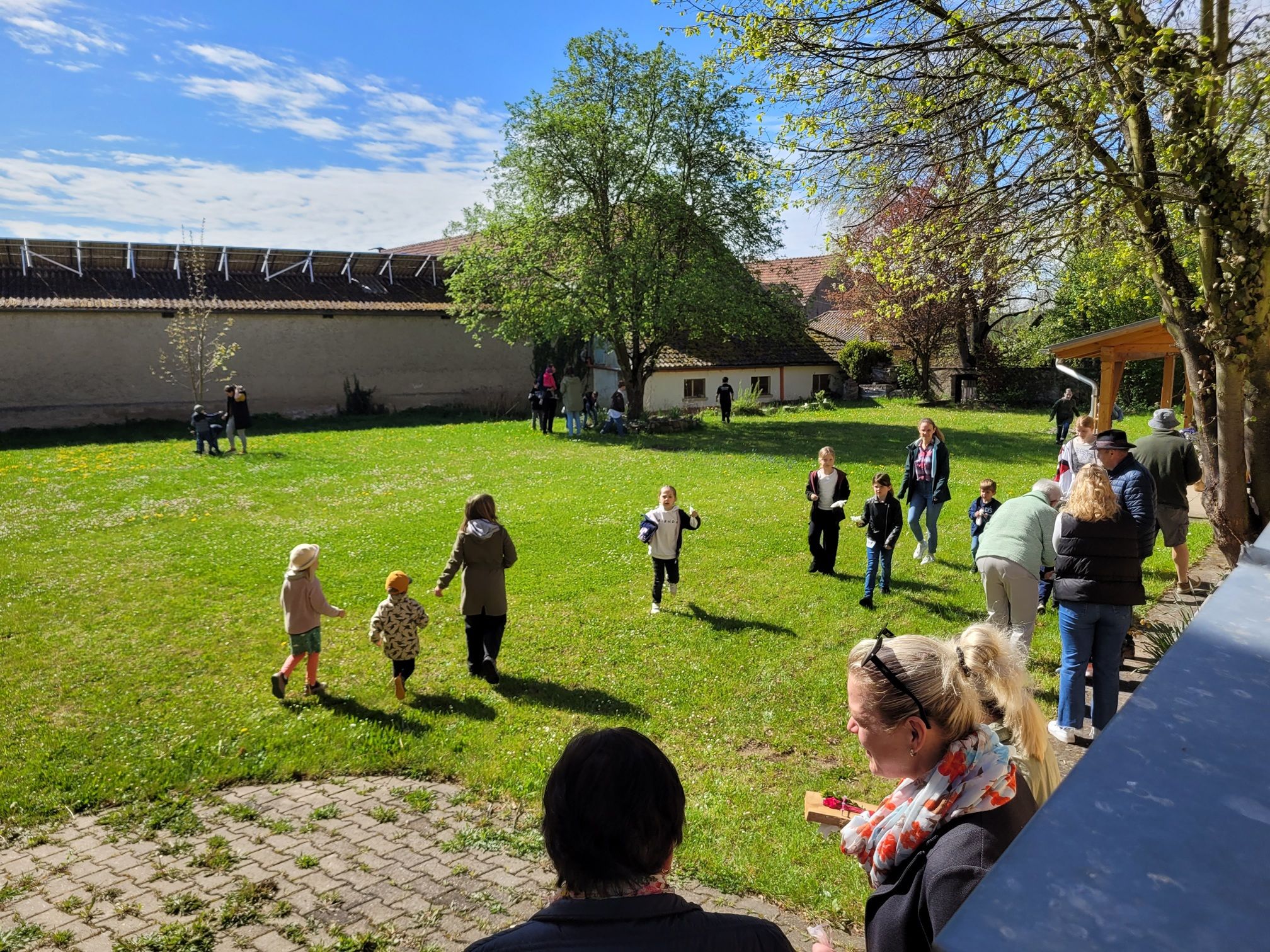 Blick auf einen großen Garten, in dem viele Kinder herumlaufen und Ostereier suchen