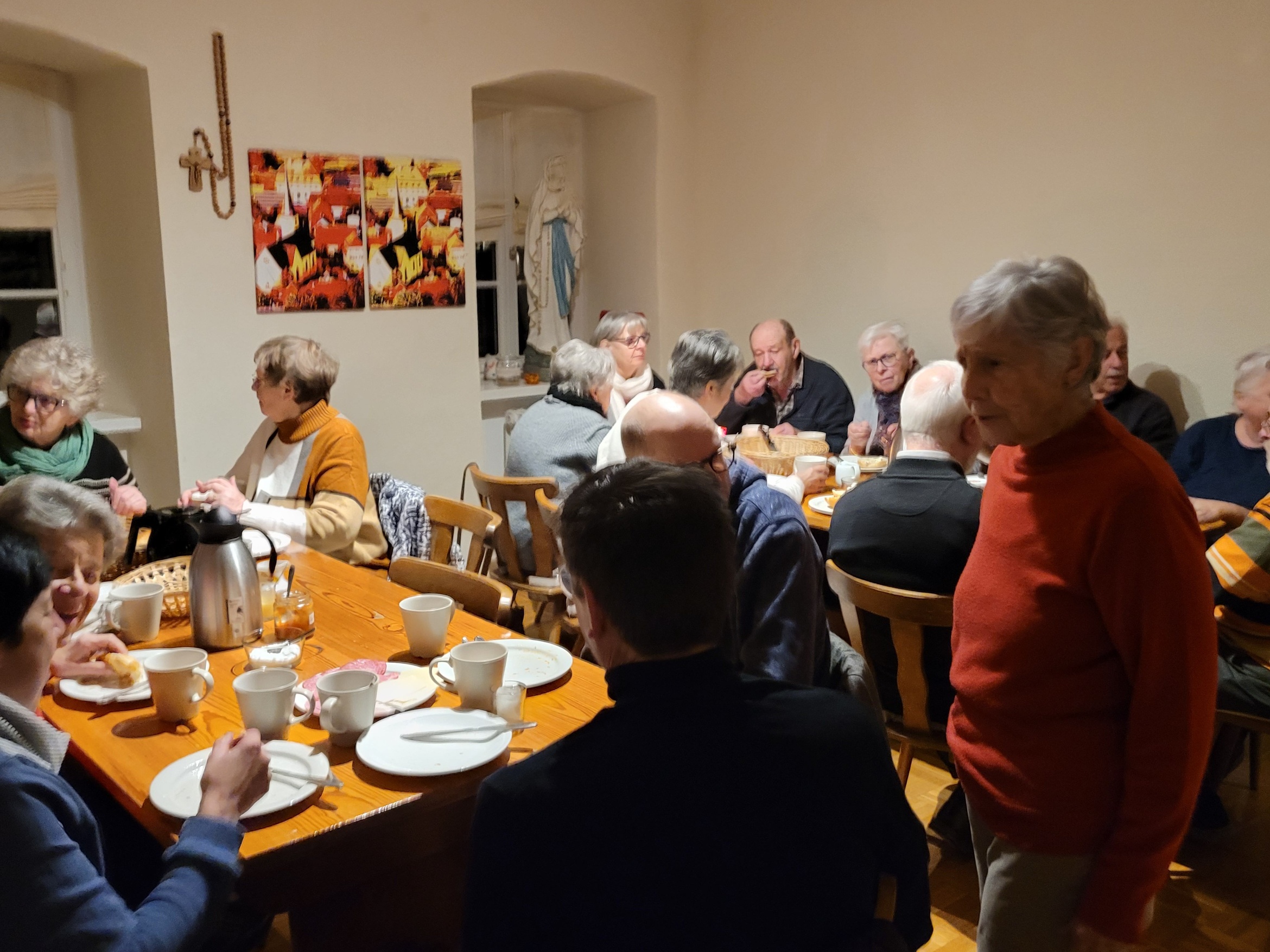 Blick auf den gut gefüllten Pfarrraum. Viele Menschen sitzen an den Tischen, frühstücken und unterhalten sich angeregt.