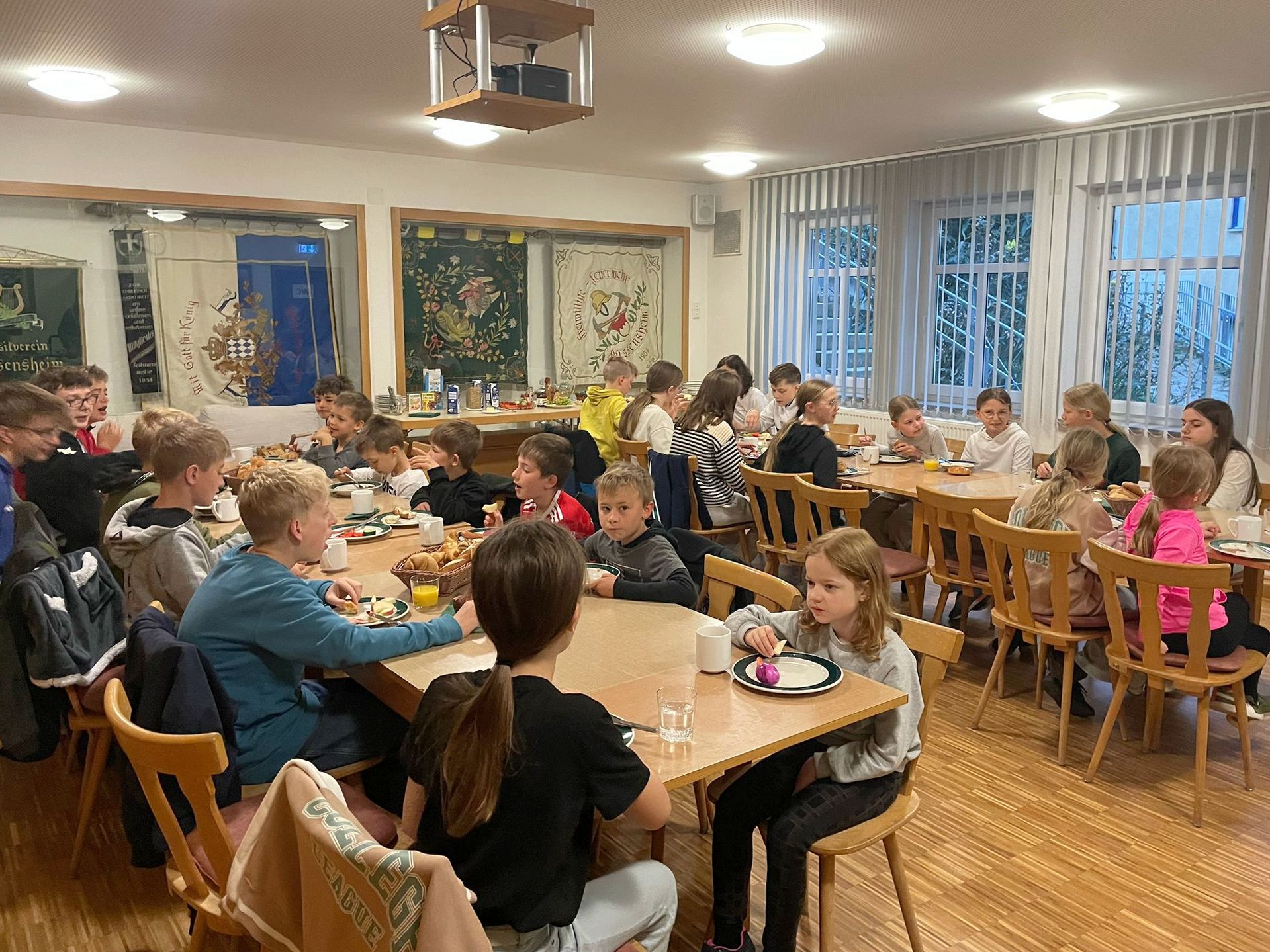 Blick in einen Raum. An den Tischen sitzen Kinder.