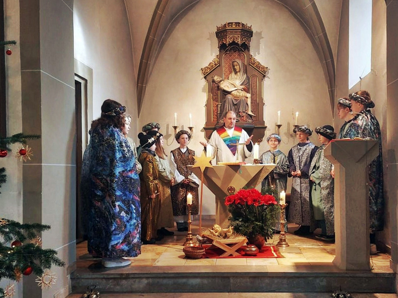 Um den Altar stehen die Sternsingerinnen und Sternsinger sowie Pastoralreferent Florian Meier.