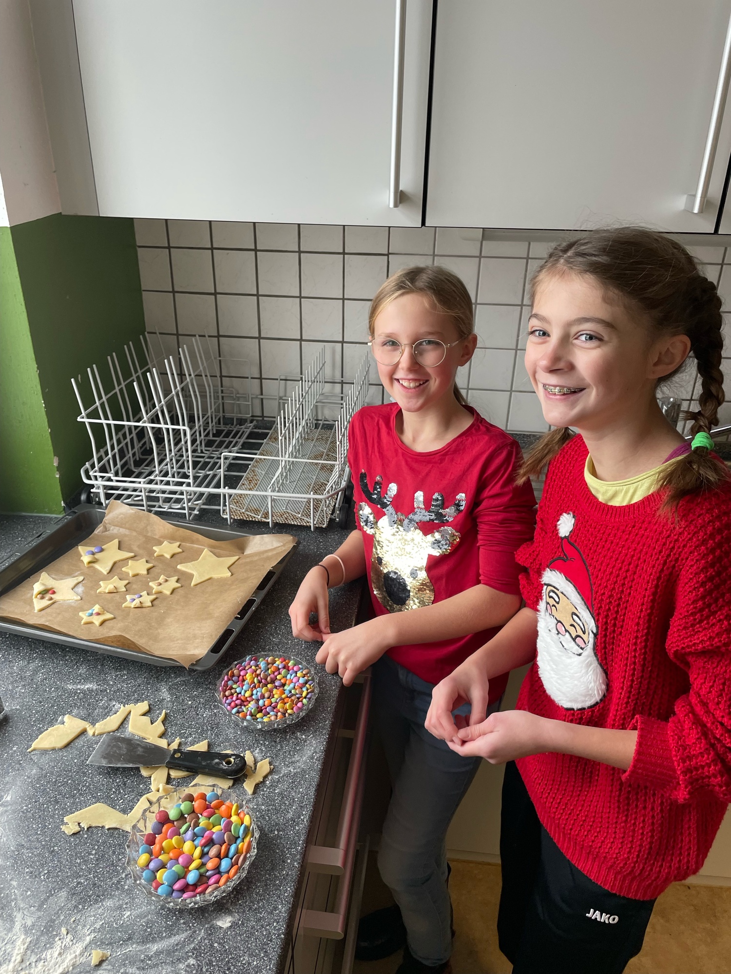 Zwei Mädchen backen Plätzchen und lächeln in die Kamera