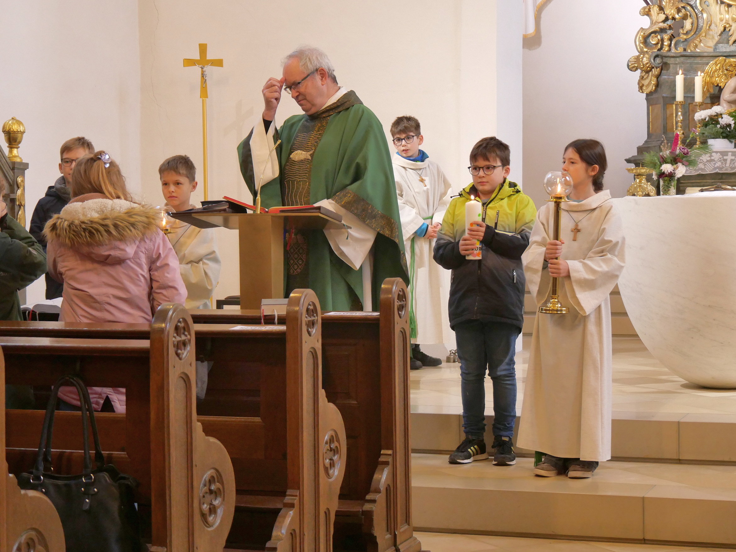 In der Pfarrkirche St. Odilia. Der Pfarrer macht gerade ein Kreuzzeichen auf die Stirn.