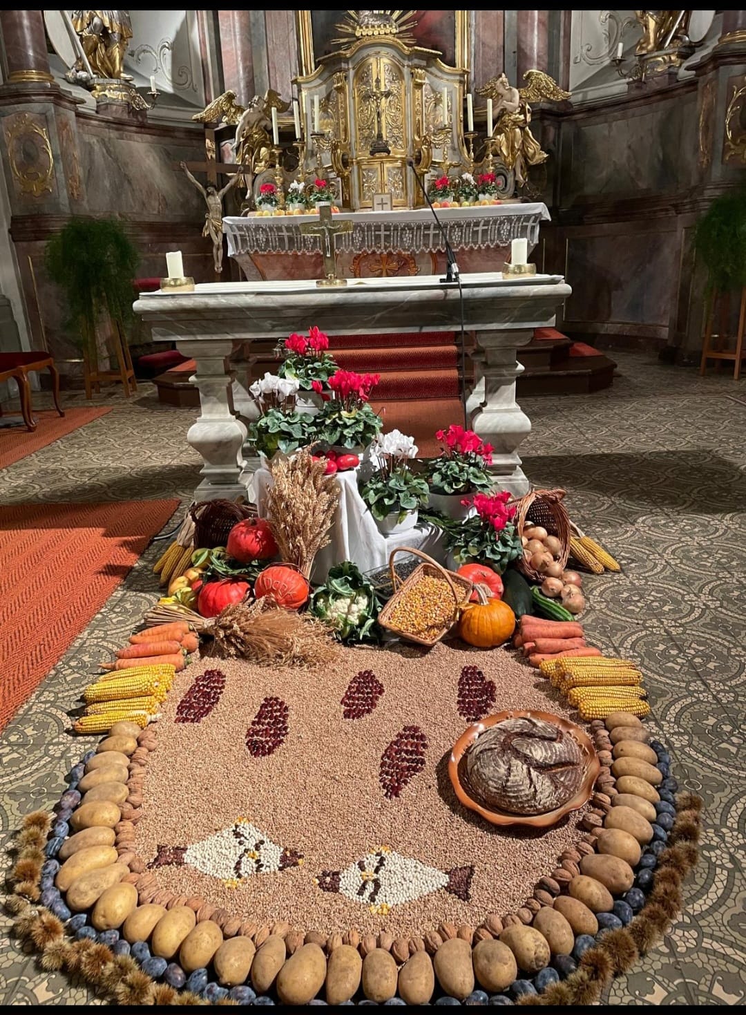 Vor dem Altar eine barocken Kirche ist ein Bodenbild aus Feldfrüchten gelegt mit den Symbolen von fünf Broten und zwei Fischen