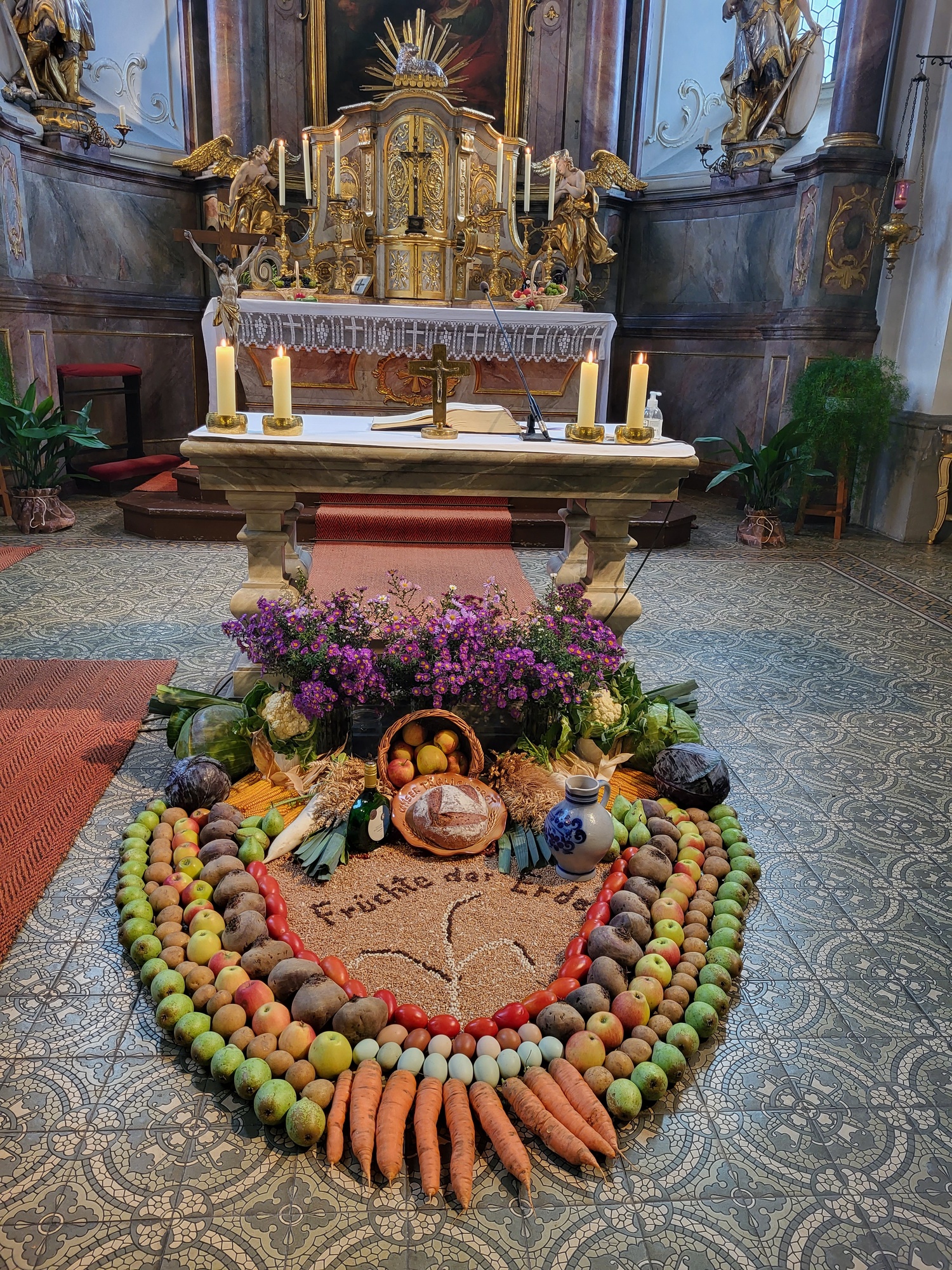 Erntegaben, kunstvoll angeordnet, im Hintergrund sieht man den Hochaltar