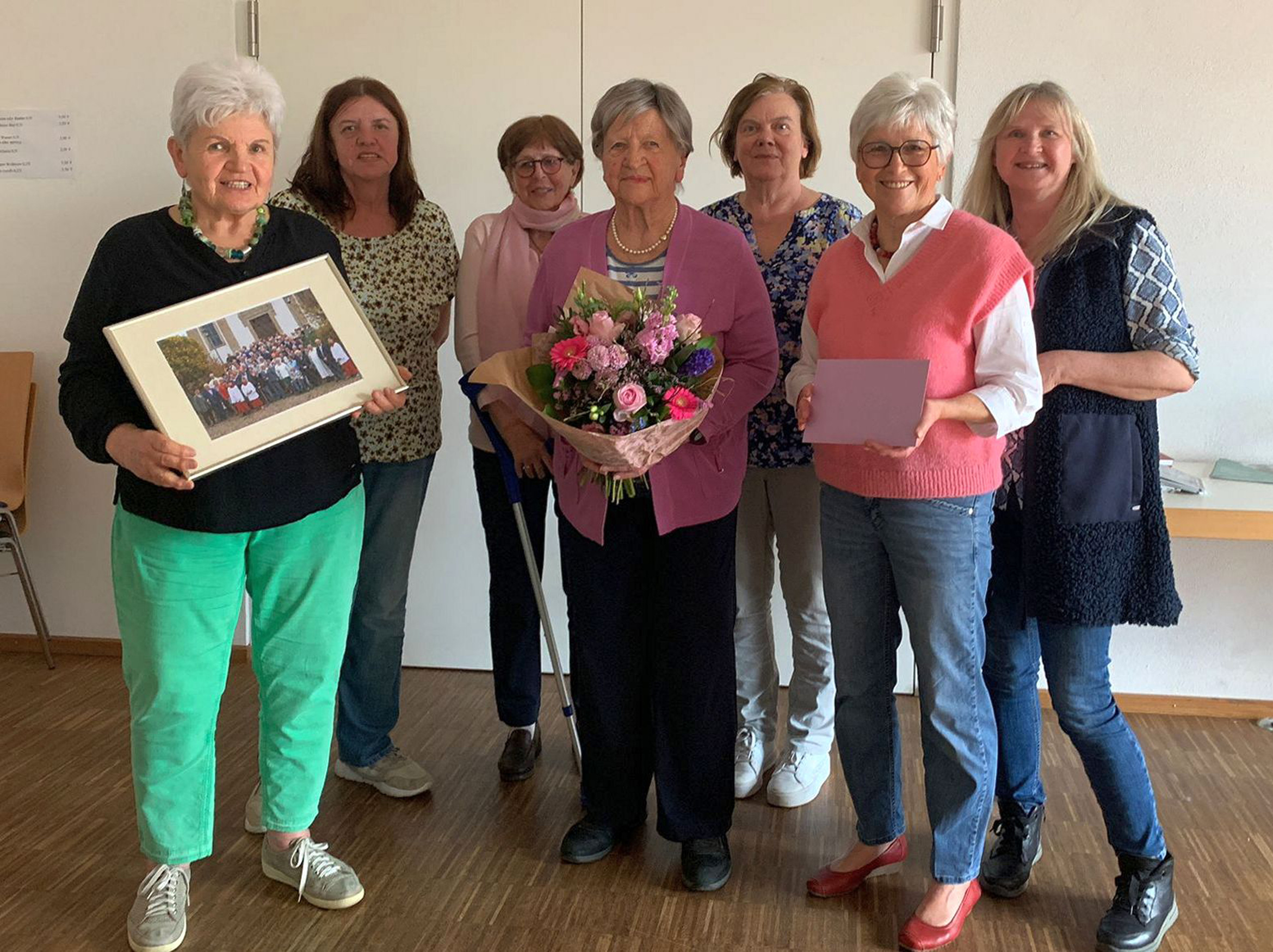 Ein Gruppenbild mit Frau Brand in der Mitte mit Blumen in der Hand.