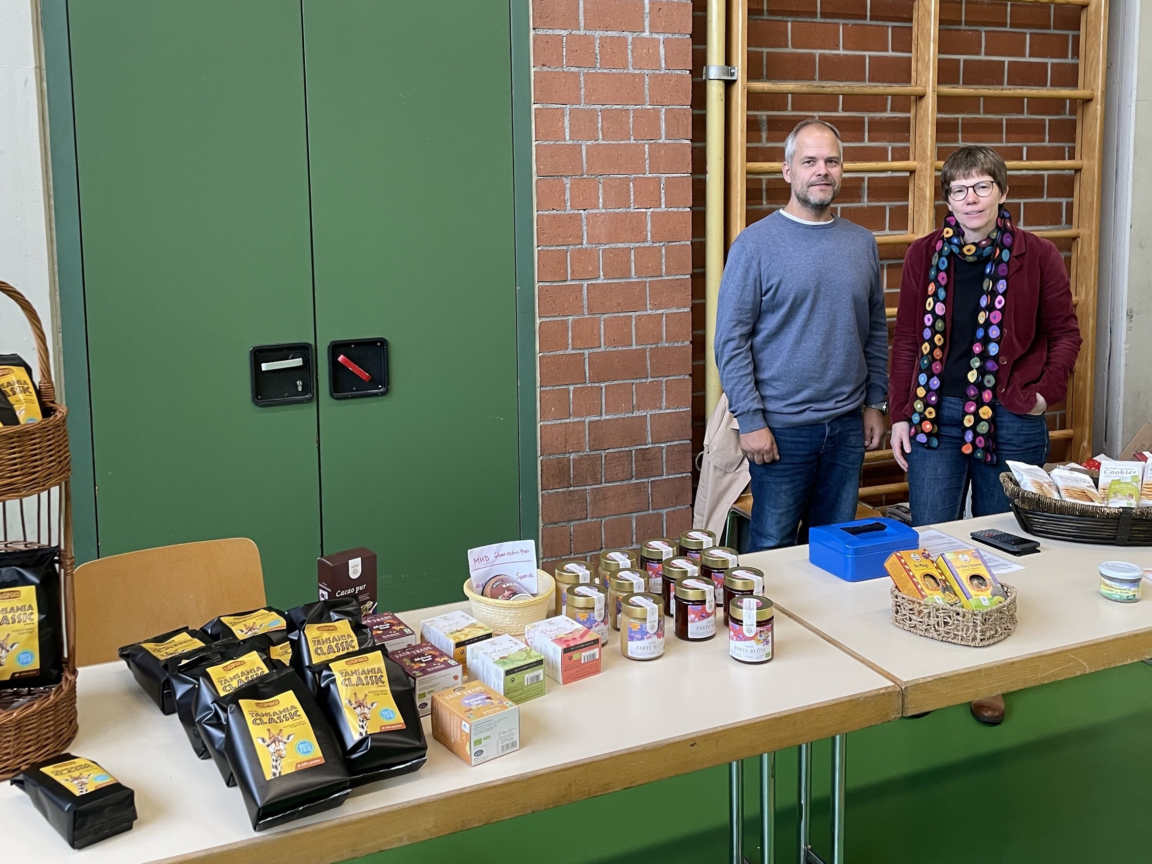 Ein Mann und eine Frau stehen hinter einem Verkaufstisch für Eine-Welt-Produkte.