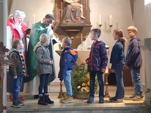 Ein Priester segnet sechs Kinder.