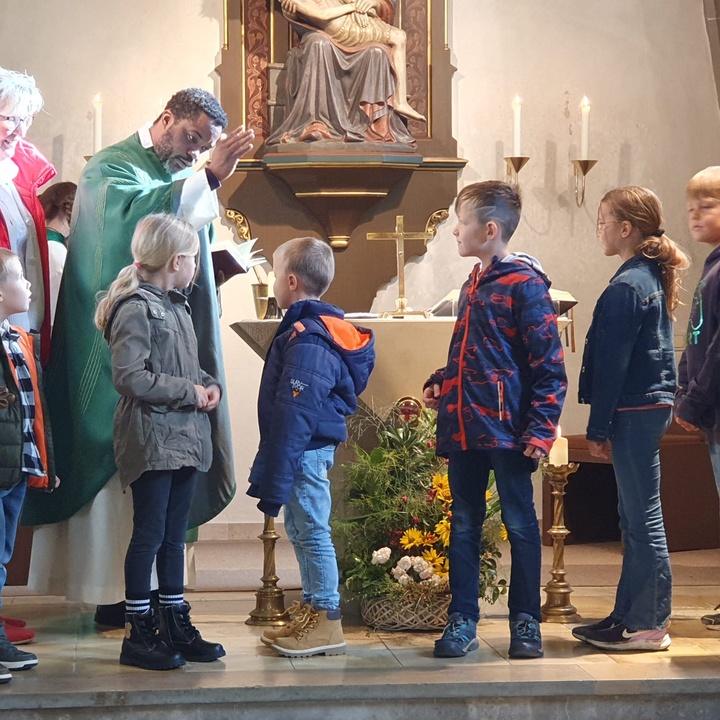 Ein Priester segnet sechs Kinder.