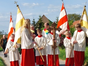 Ministrant:innen stehen mit Prozessionsfahnen und Kreuz in einer Gruppe zusammen.