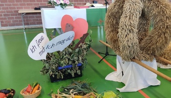 Das Foto zeigt einen Erntealtar mit verschiedenen Früchten und einer Erntekrone. Auf Schildern steht: "Ich freue mich" und "ich mag dich"