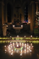 Der Altarraum der Kirche in Prosselsheim ist nur durch Kerzen erleuchtet, im Vordergrund auf dem Boden stehen auch einige Kerzen.