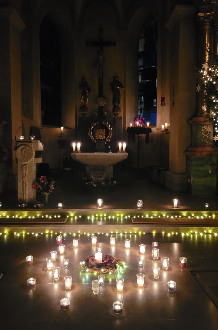 Der Altarraum der Kirche in Prosselsheim ist nur durch Kerzen erleuchtet, im Vordergrund auf dem Boden stehen auch einige Kerzen.