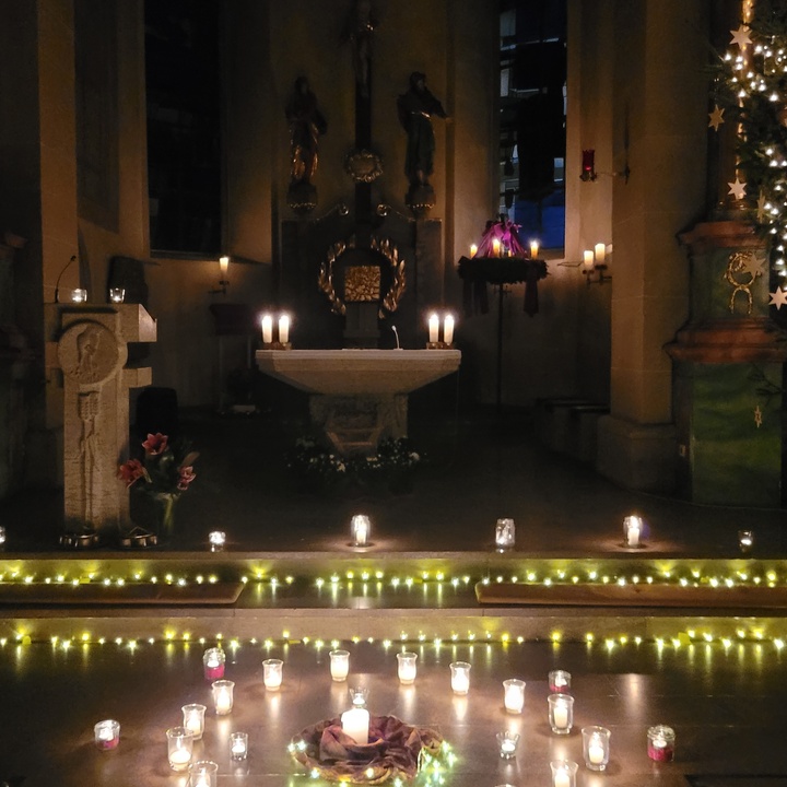 Der Altarraum der Kirche in Prosselsheim ist nur durch Kerzen erleuchtet, im Vordergrund auf dem Boden stehen auch einige Kerzen.