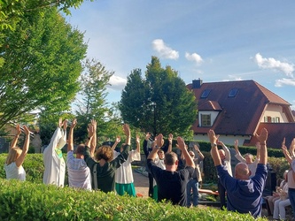 Auf dem Friedhof in Püssensheim stehen Menschen und hebe die Hände in die Höhe.