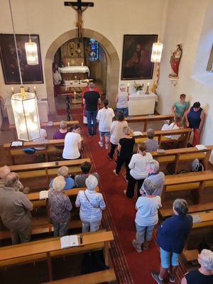 Ein Bild von den Eporen aus ins Kirchenschiff, wo sich im Mittelgang mehrere Menschen zum Empfang der Kommunion anstellen.