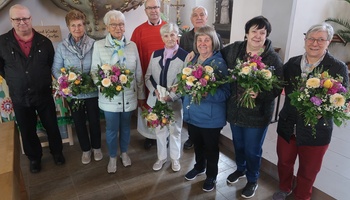Auf dem Foto stehen neun Frauen und Männer zusammen. Die Frauen halten Blumensträuße in den Händen.