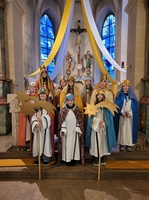 Zehn Kinder stehen als Sternsinger verkleidet vor dem Altar und schauen in die Kamera