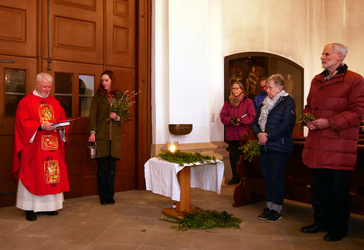 An der hinteren Kirchentür stehen der Pfarrer und mehrere Gläubige zur Palmenweihe.