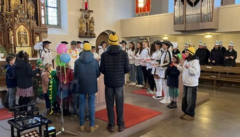 In der Kirche St. Martin in Burggrumbach stehen Kinder und Jugendliche in Faschingskostümen um den Altar.
