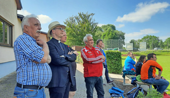 Vier Männer schauen am Spielfeldrand einem Fußballspiel zu. Unter ihnen ist Bischof Franz Jung.