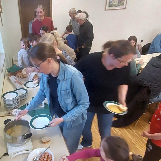 Eine Gruppe mit Erwachsenen und Kindern beim Essen holen.
