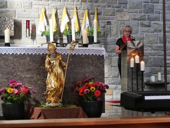 Blick in den Chorraum. Man sieht die Figur des heiligen Ägidius vor dem Altar und hinten rechts die Lektorin am Ambo.