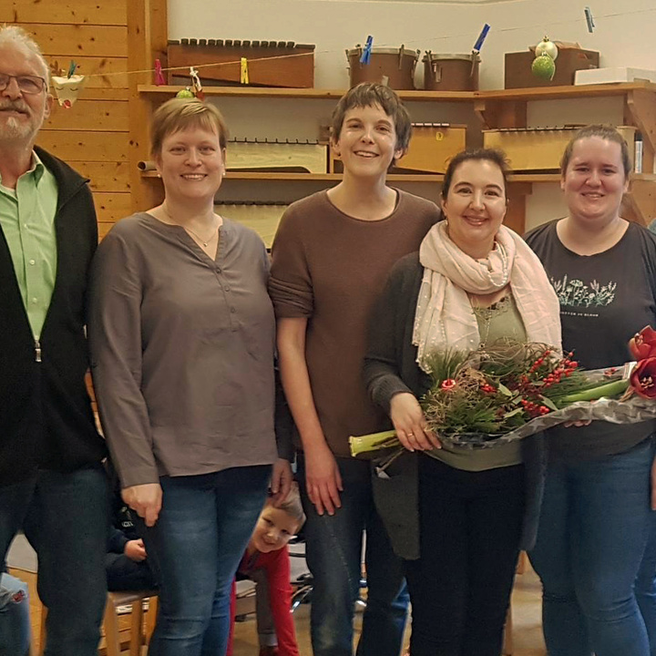 Auf einem Gruppenbild mit sechs Personen hält die Jubilarin einen Blumenstrauß in der Hand.