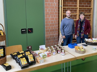 Ein Mann und eine Frau stehen hinter einem Verkaufstisch für Eine-Welt-Produkte.