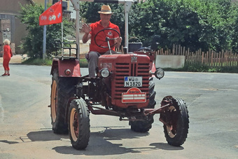 Ein roter Oldtimer-Traktor fährt vorbei.