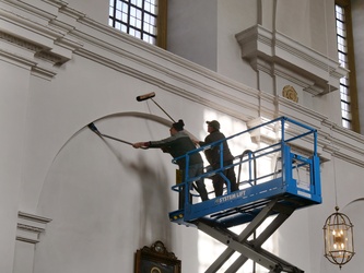 Zwei Männer stehen in der Hebebühne und haben Besen in den Händen.