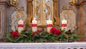 Auf dem Seitenaltar steht das Adventsgesteck. Drei Kerzen brennen.