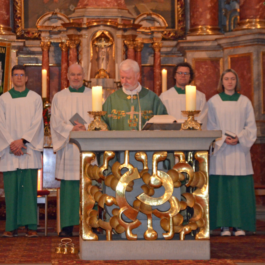 Eine Gruppe mit sechs Personen steht hinter dem Altar.