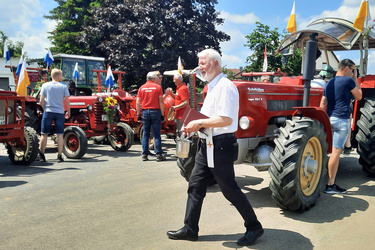 Pater Matthäus geht an den Traktoren vorbei und besprengt sie mit Weihwasser.