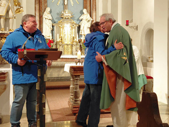 André und Sonja Ziegler übergeben Pfarrer Rügamer in der Kirche den Orden.