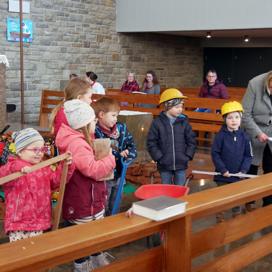 Im Altarraum der Kiche in Dipbach sind ein paar Kinder. Sie haben Gegenstände in den Händen, beispielsweise eine Zollstock.
