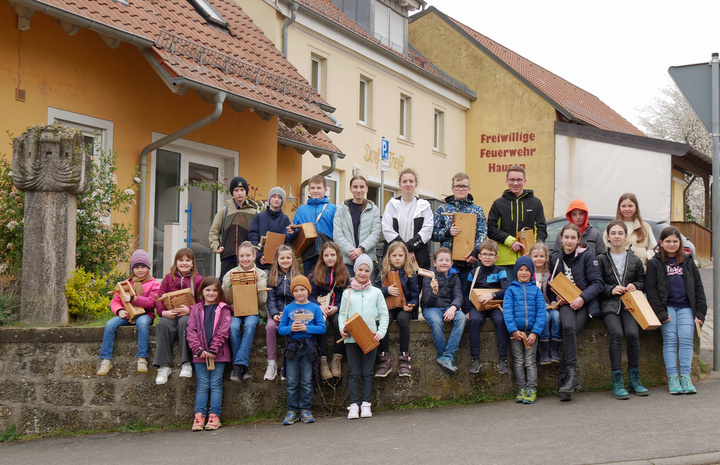 Ein schönes Gruppenbild vor einer Mauer. Kinder sitzen auf der Mauer oder stehen davor oder dahinter.