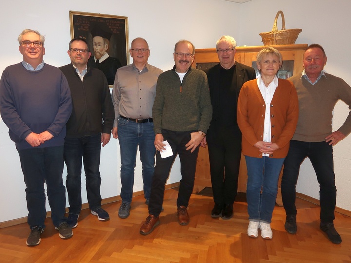 Das ist ein Gruppenbild mit sieben Personen. Der Pfarrer ist der dritte von rechts.