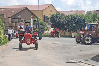 Mehrere Oldtimer-Traktoren stehen auf einem Parkplatz.