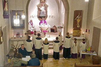 Blick von der Empore in den Altarraum mit dem Priester am Altar und Ministranten von hinten.