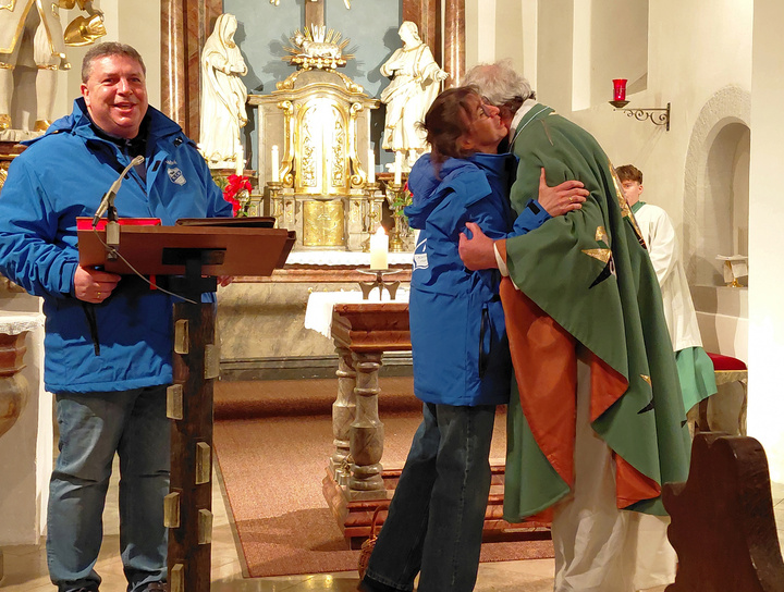 André und Sonja Ziegler übergeben Pfarrer Rügamer in der Kirche den Orden.