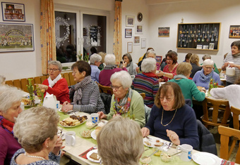 Frauen sitzen an zwei gedeckten. Sie unterhalten sich und essen etwas.
