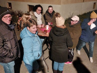 Eine kleine Gruppe an Menschen steht in winterlicher Kleidung um einen Stehtisch.